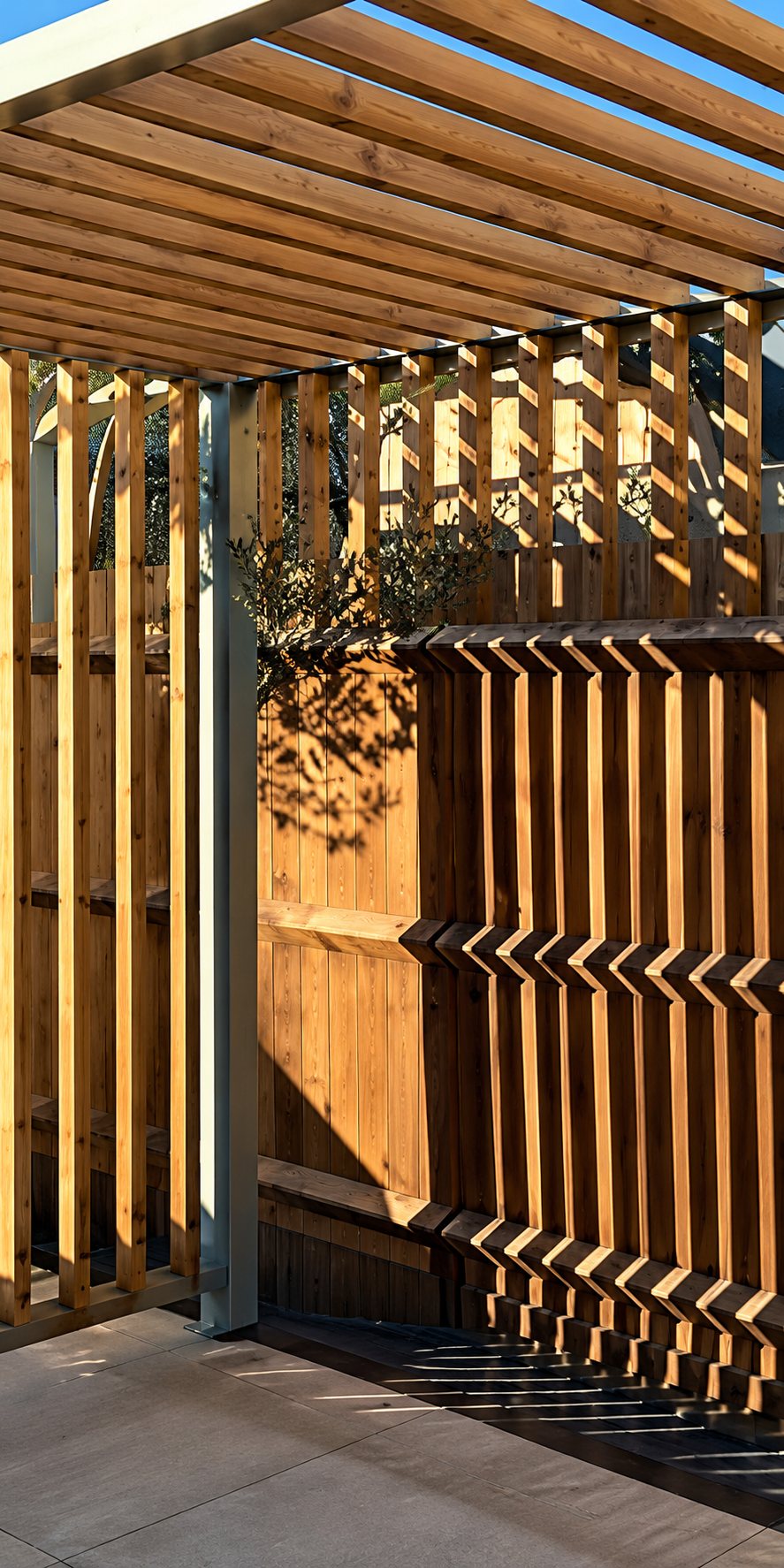 Une pergola en bois avec une clôture à lames verticales, éclairées par le soleil au-dessus d'une terrasse.