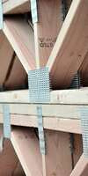 Gros plan sur une structure de charpente en bois avec des plaques de connexion métalliques galvanisées assemblant les poutres.